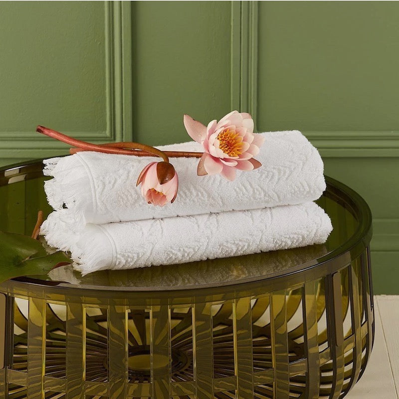 yves delorme flores hand towels on green table against green wall with pink flowers on them for fig linens and home