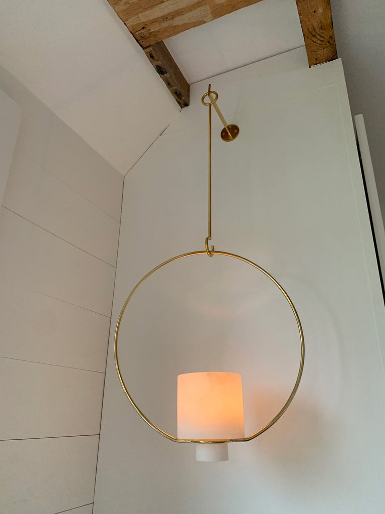 M+A NYC Alabaster Hanging Planter/Lantern with a lit glass votive inside.