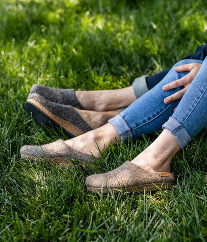 Two people wearing the comfy Stegmann clogs during the summer in the grass.