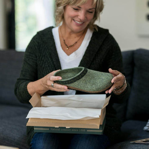 A woman holding her new Original 108 Clog - Sage colorway as she opens the shoe box.