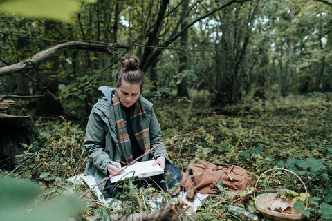 Agnes sitting in a wood nature journaling