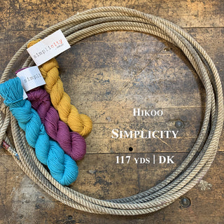A photo of three hanks of Simplicity yarn in a lasso on a wooden surface