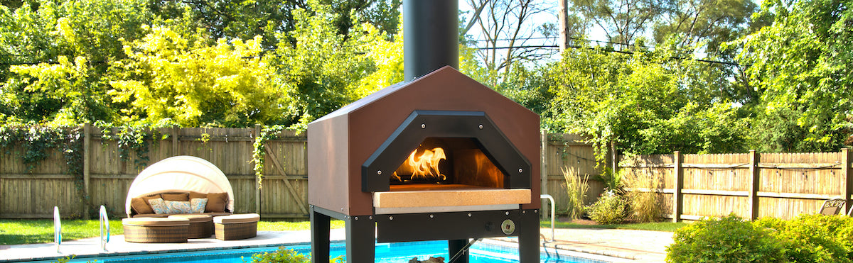 Gas pizza oven sitting in a backyard in front of a pool