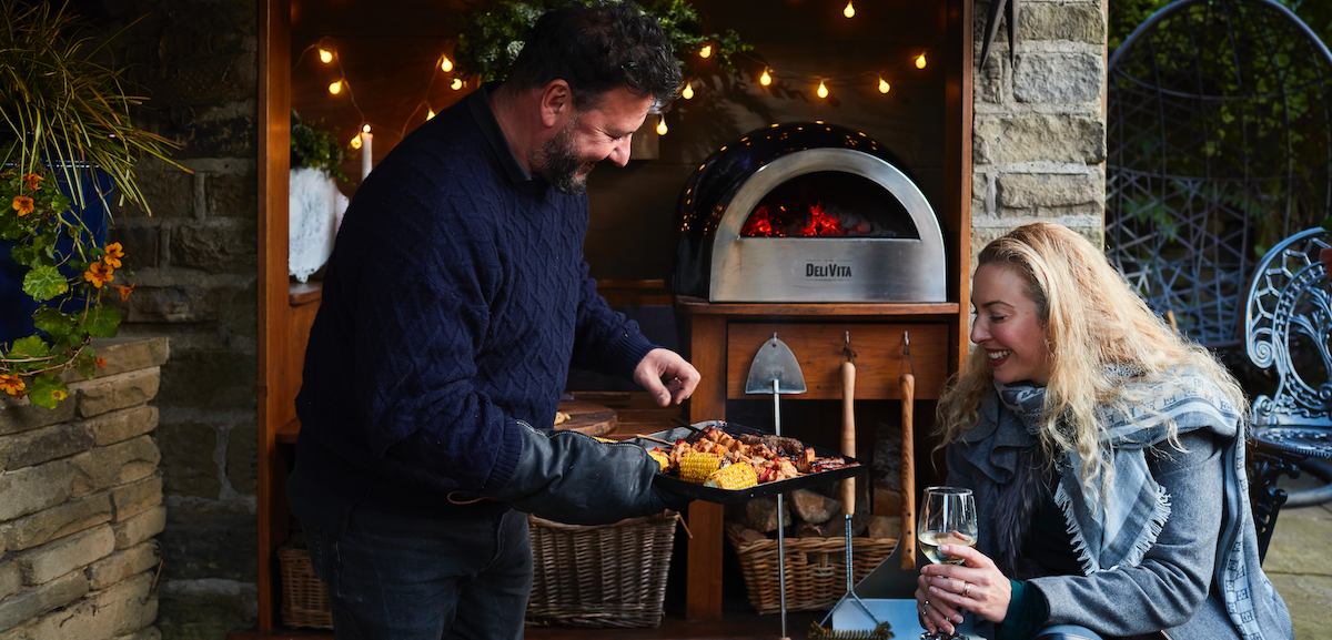 Man and woman cooking in a wood fired pizza oven