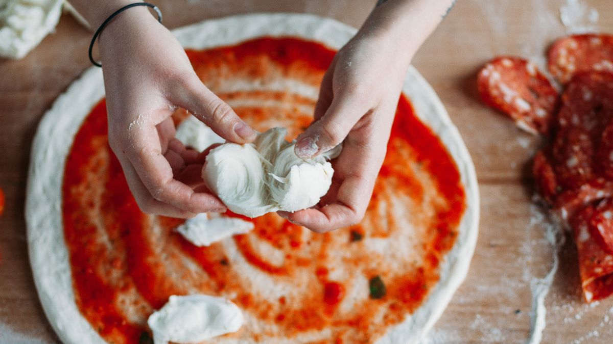 Putting buffalo mozzarella cheese on Neapolitan style pizza dough