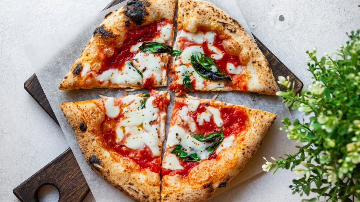 Neapolitan-style pizza cut into 4 sections with a pizza peel