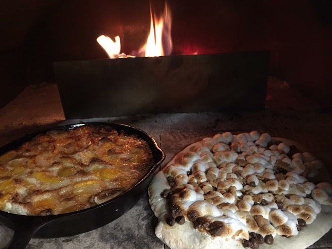 Peach cobbler and s'mores cooking in pizza oven
