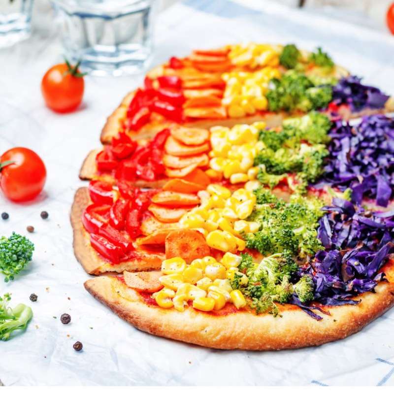 Plant-based pizza with peppers, carrots, corn broccoli, and cabbage toppings