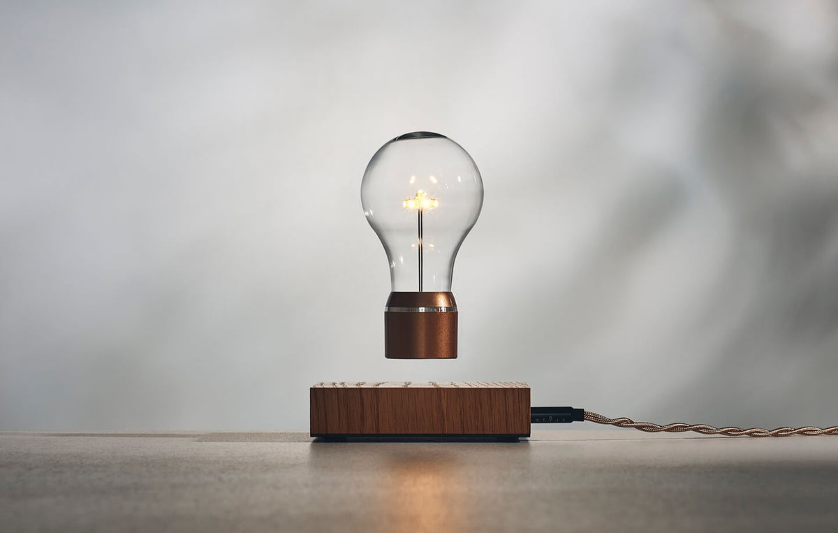 Levitating light bulb Edison collection, oak wood base, golden cap bulb on a light background