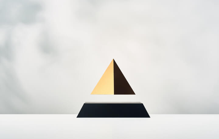 Levitating pyramid Py with black base and gold top on a light background