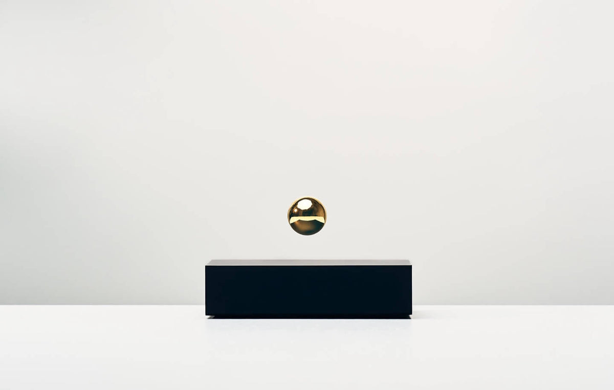 Buda Ball levitating sphere, black base, gold sphere on a light background