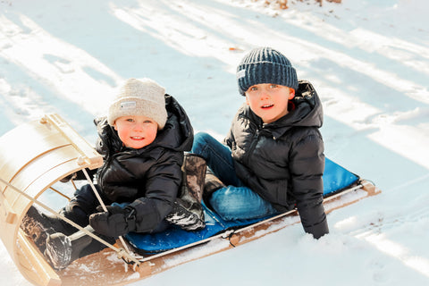 Two kids on toboggan outdoors 