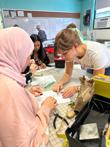 A volunteer helping during a Forai Jewelry Making Training