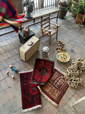 photo of props used in the campaign photoshoot including a vintage suitcase, 3 small rugs, rope, antique bicycle toy, glass blown bugs, a wooden chair