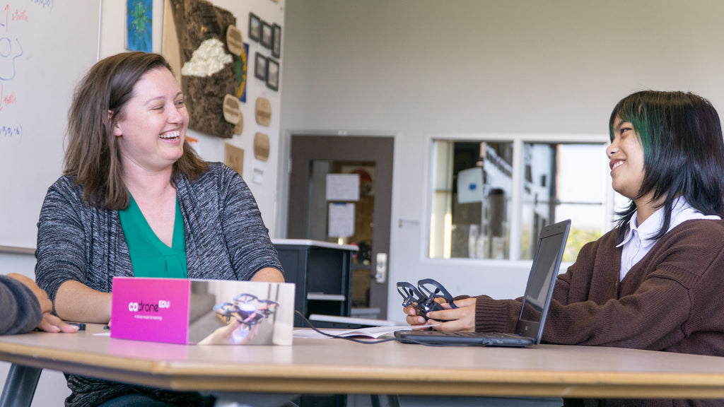 A teacher coaching a student about drones while she holds the CoDrone EDU