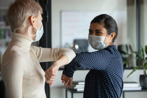 Two women with face masks working as a team in their job