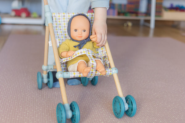 Pomea doll sitting in stroller with child holding doll's hand