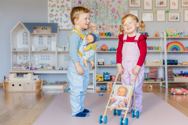 Twin toddlers playing with pomea dolls and accessories in playroom