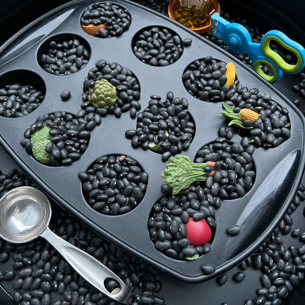 Black beans used in hide and seek sensory play in cupcake tray