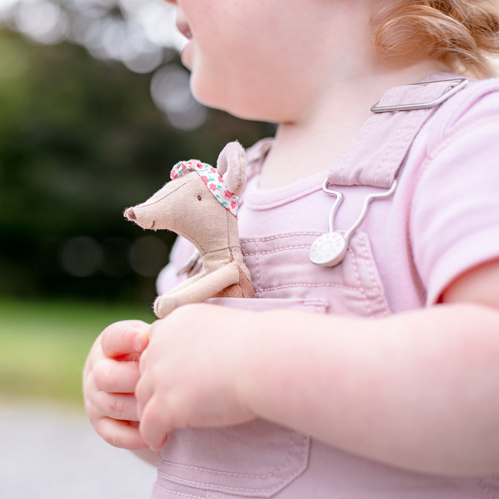Little girl holding Maileg mice in her top overalls pocket
