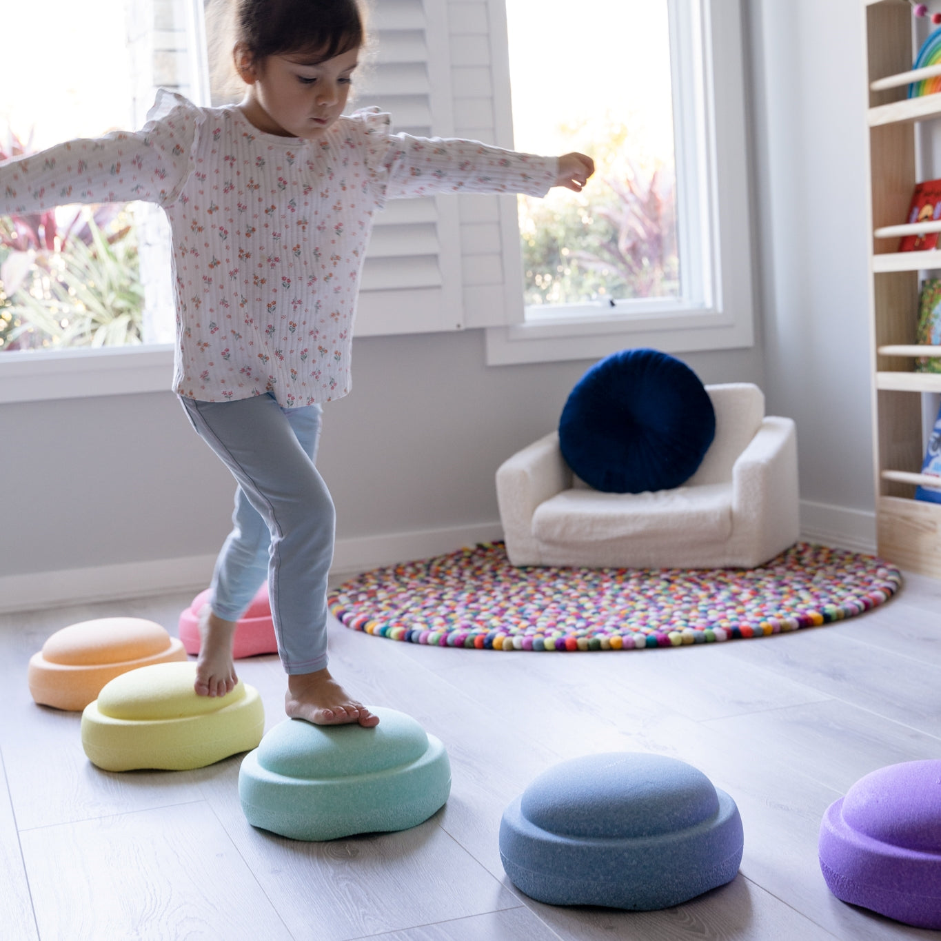 Indoor playroom with child walking on pastel stacking stones from Stapelstein