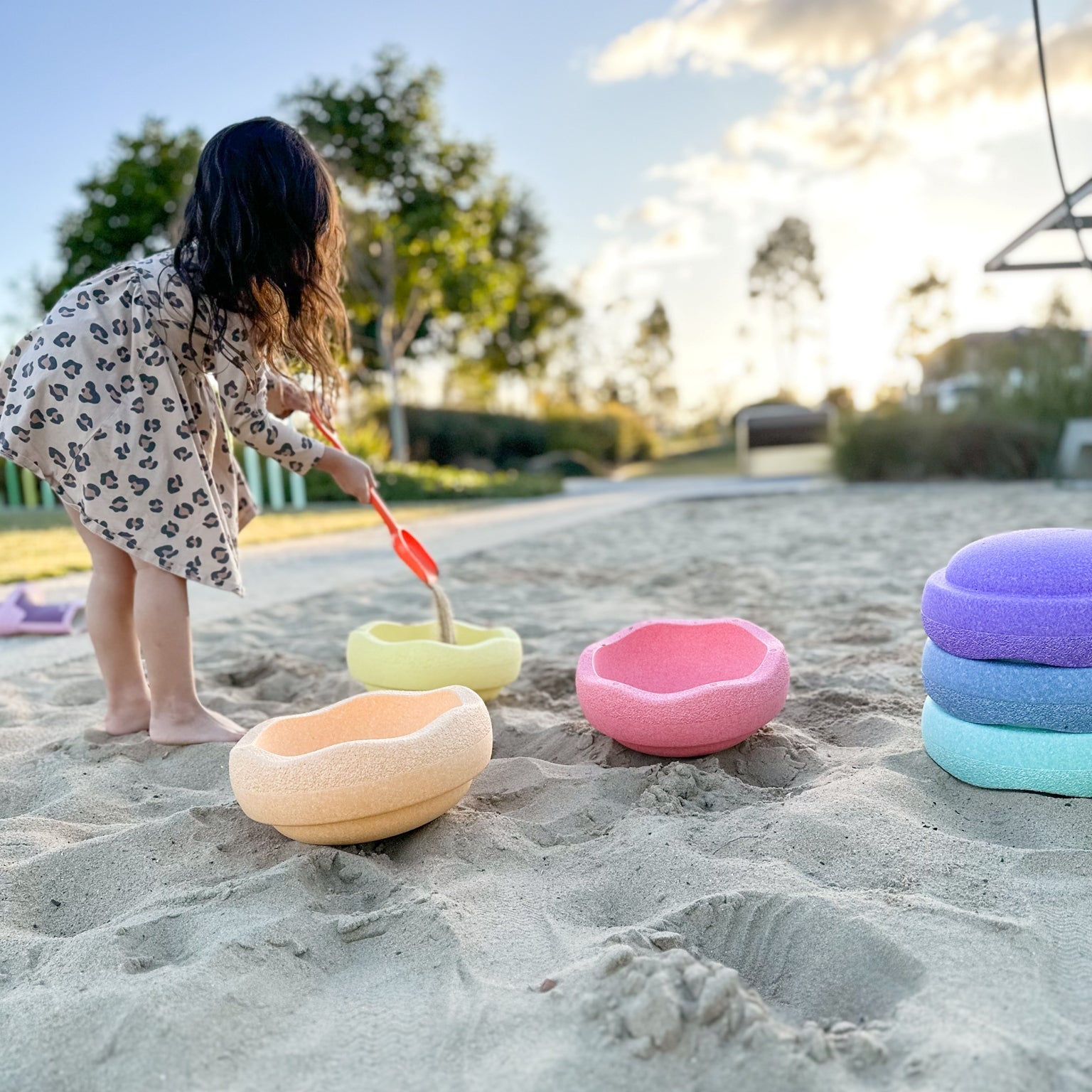 Child pouring sand into pastel stacking stones from Stapelstein in playground