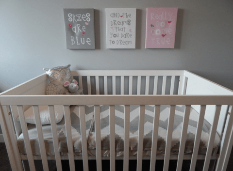 How to decorate - a modern nursery with a white crib, grey wall and art in grey, white and pink.