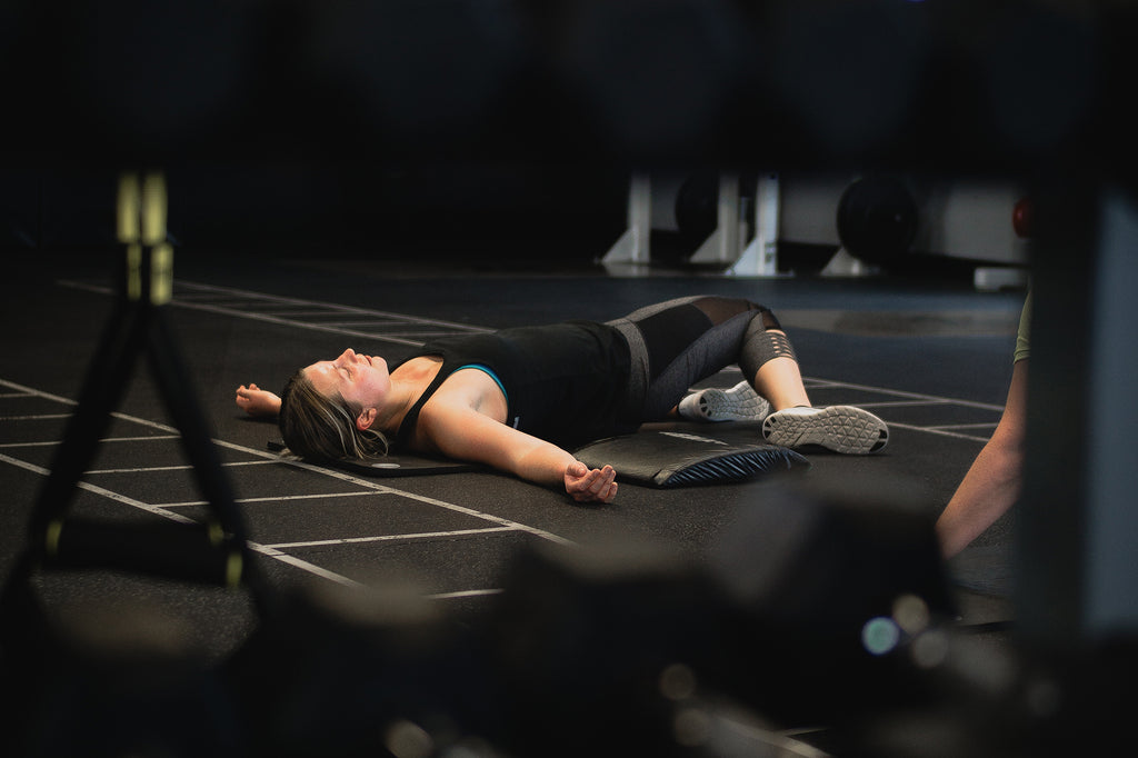 A woman is lying down on the floor inside a gym.