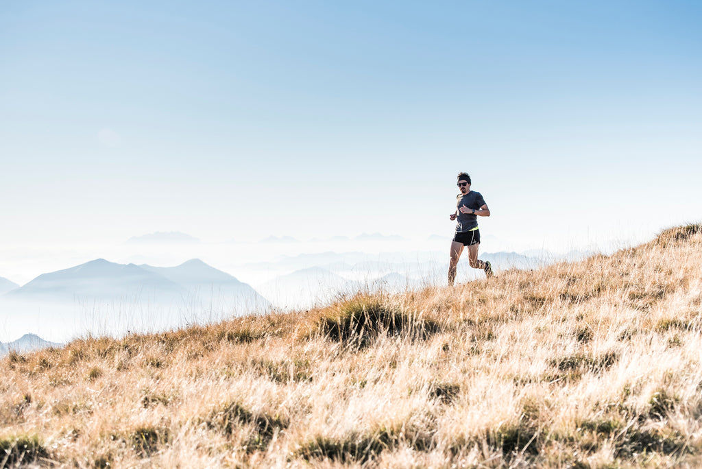 A fell runner is running through the mountain during daylight.