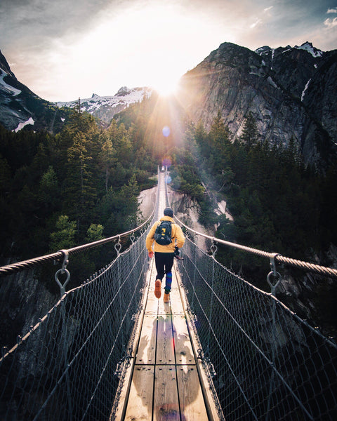 A person is running across a wooden bridge in the mountains.