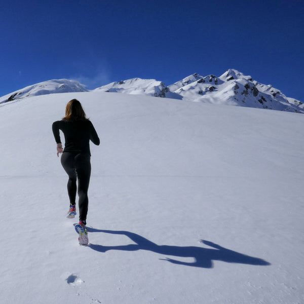 A woman is running upward the mountain during winter.