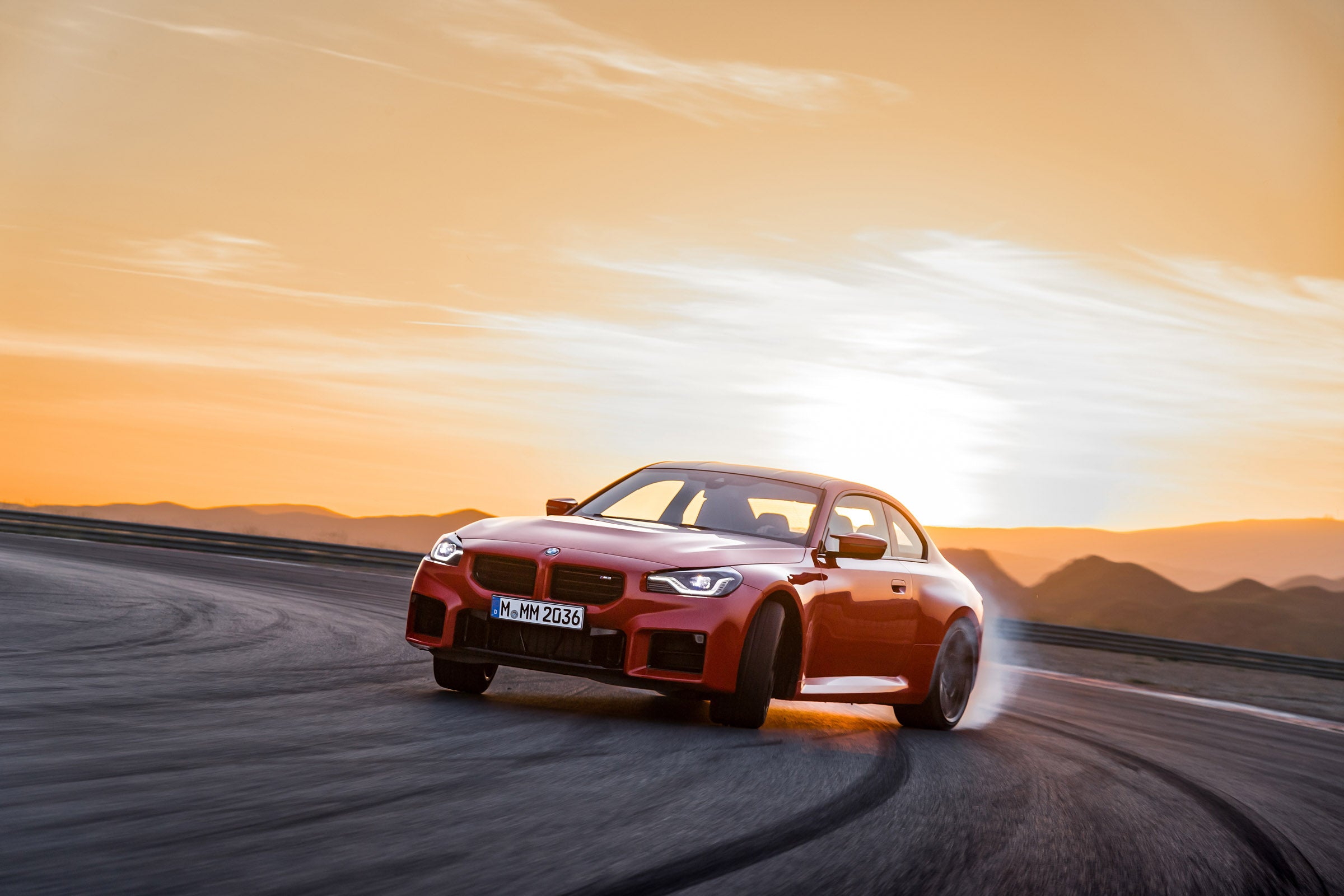 2023 BMW G87 M2 in Toronto Red Drifting on track with a sun set in the background