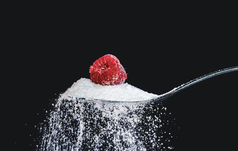 a raspberry on a spoon overflowing with artificial sugar