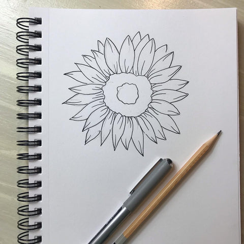 a pencil and pen drawing of a sunflower on a spiral bound drawing pad