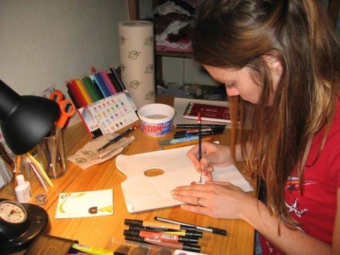 A woman holding a paintbrush and working at a table
