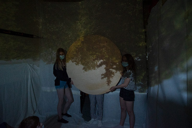 The children are holding a wooden board as a Camera obscura image frame.
