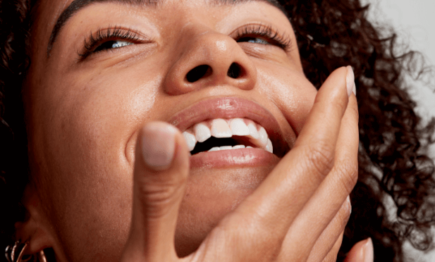 woman smiling touching her face
