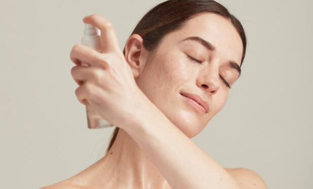 woman spraying face with toner