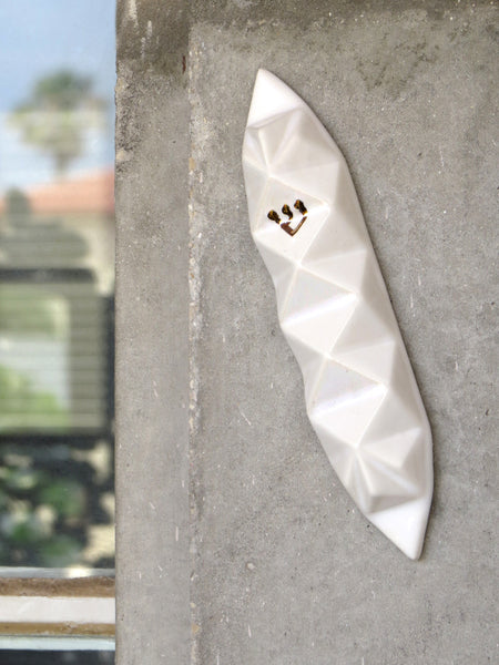Modern ceramic Mezuzah case, white with gold Shin, placed on a doorpost in 'Neve Tzedek', Tel Aviv