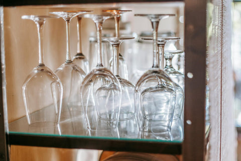 Wine glasses being storage upside down on a glass shelf