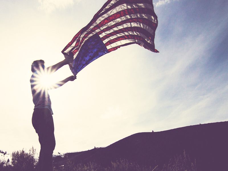 Man vertically waving american flag