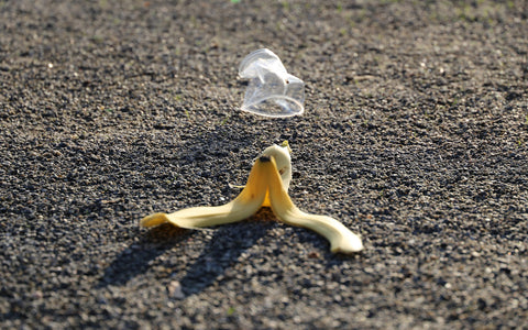 A banana peel and plastic cup on the ground