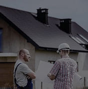 2 people stand in front of a house