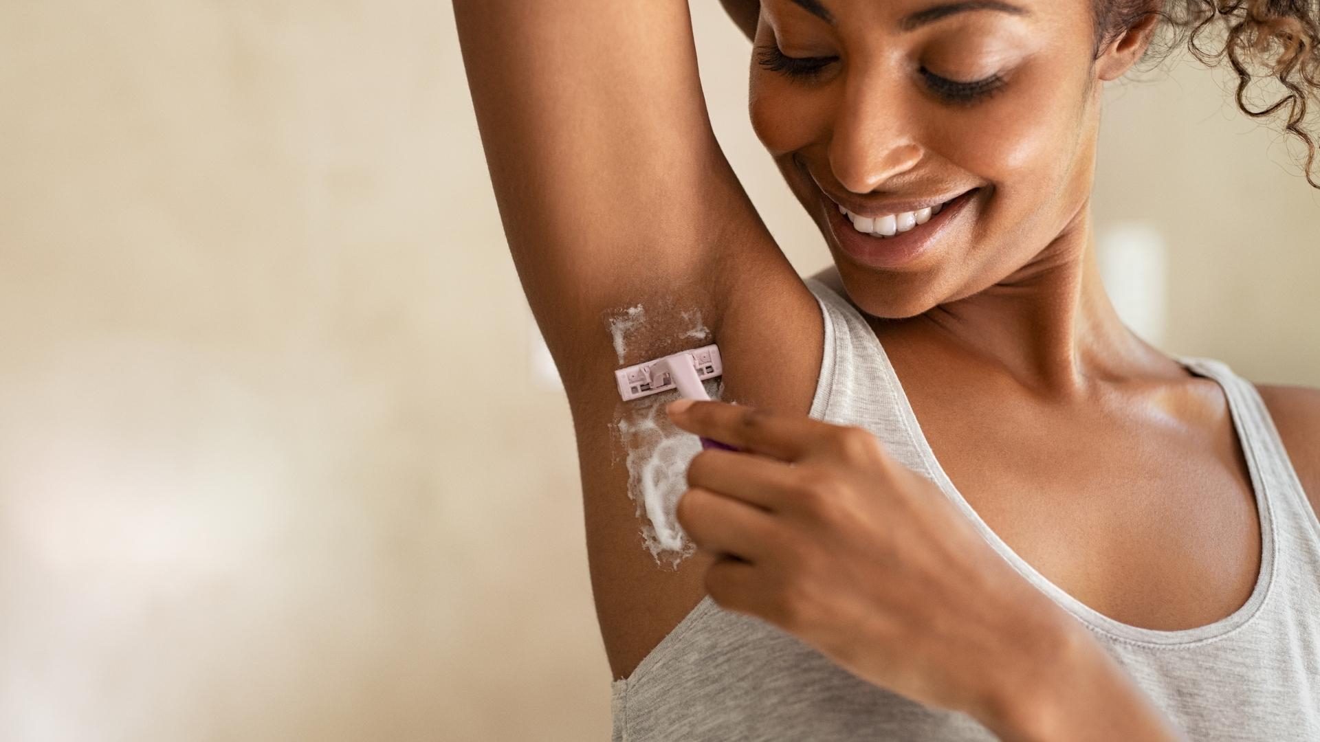 Close up image of a woman shaving your armpits with a razor and shaving cream