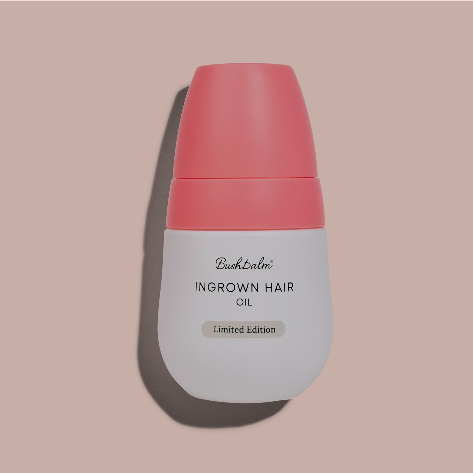 A bottle of ingrown hair oil labeled 'Bushbalm' against a pink background.