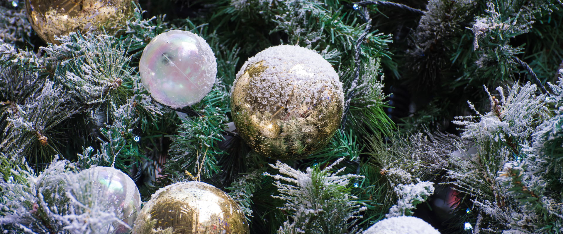 A close-up of a Christmas tree decorated with baubles and fake snow