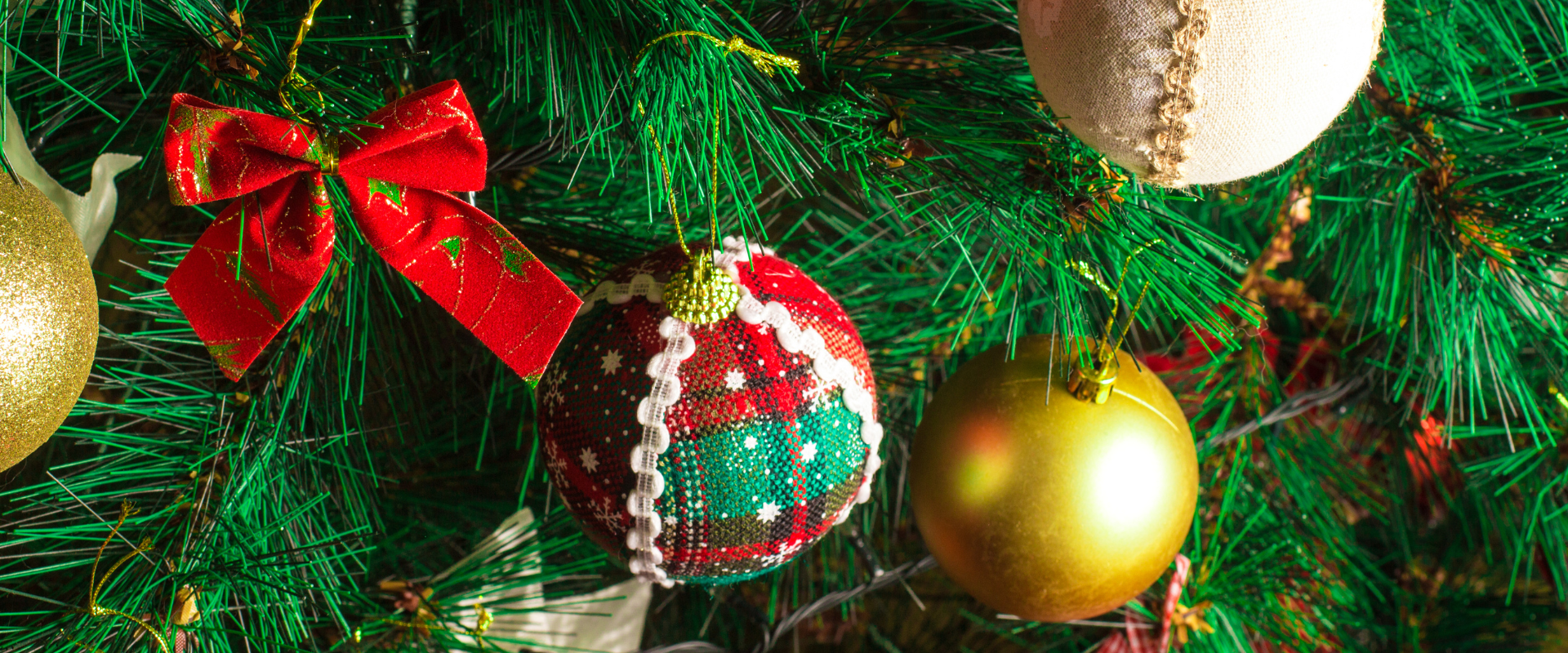 A close-up of an artificial Christmas tree decorated with baubles and ribbons