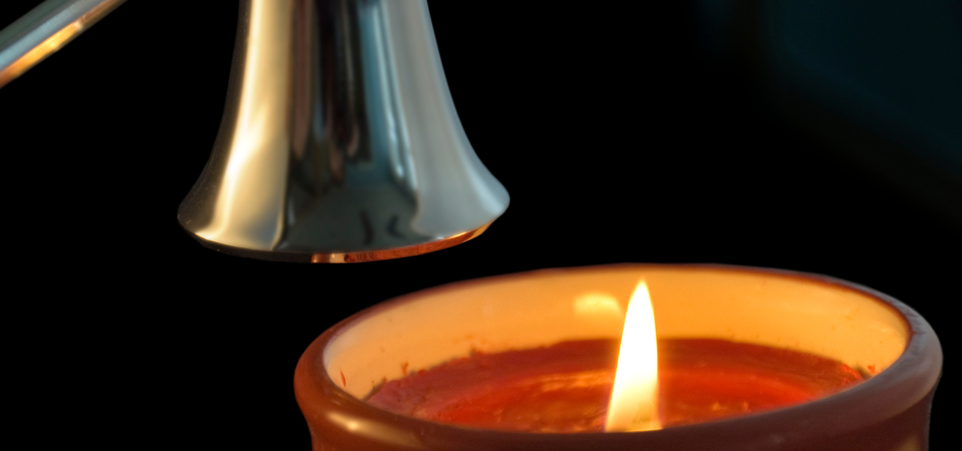 A flame snuffer above a lit candle