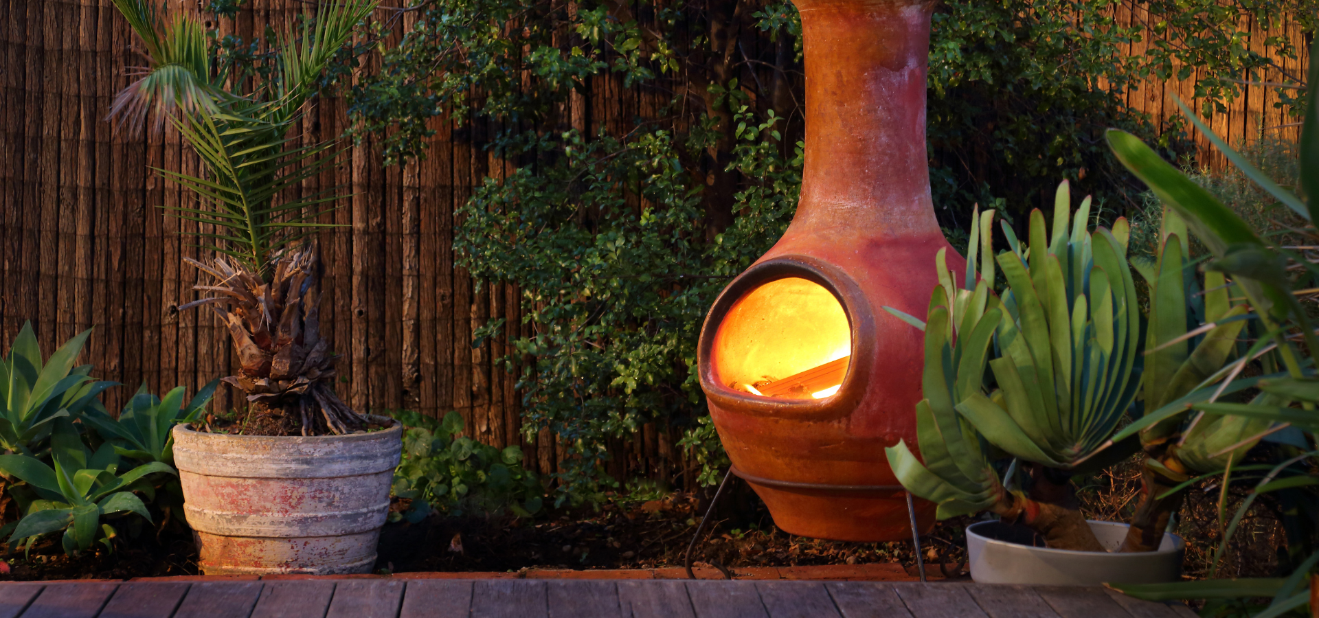 A lit clay chiminea in a garden