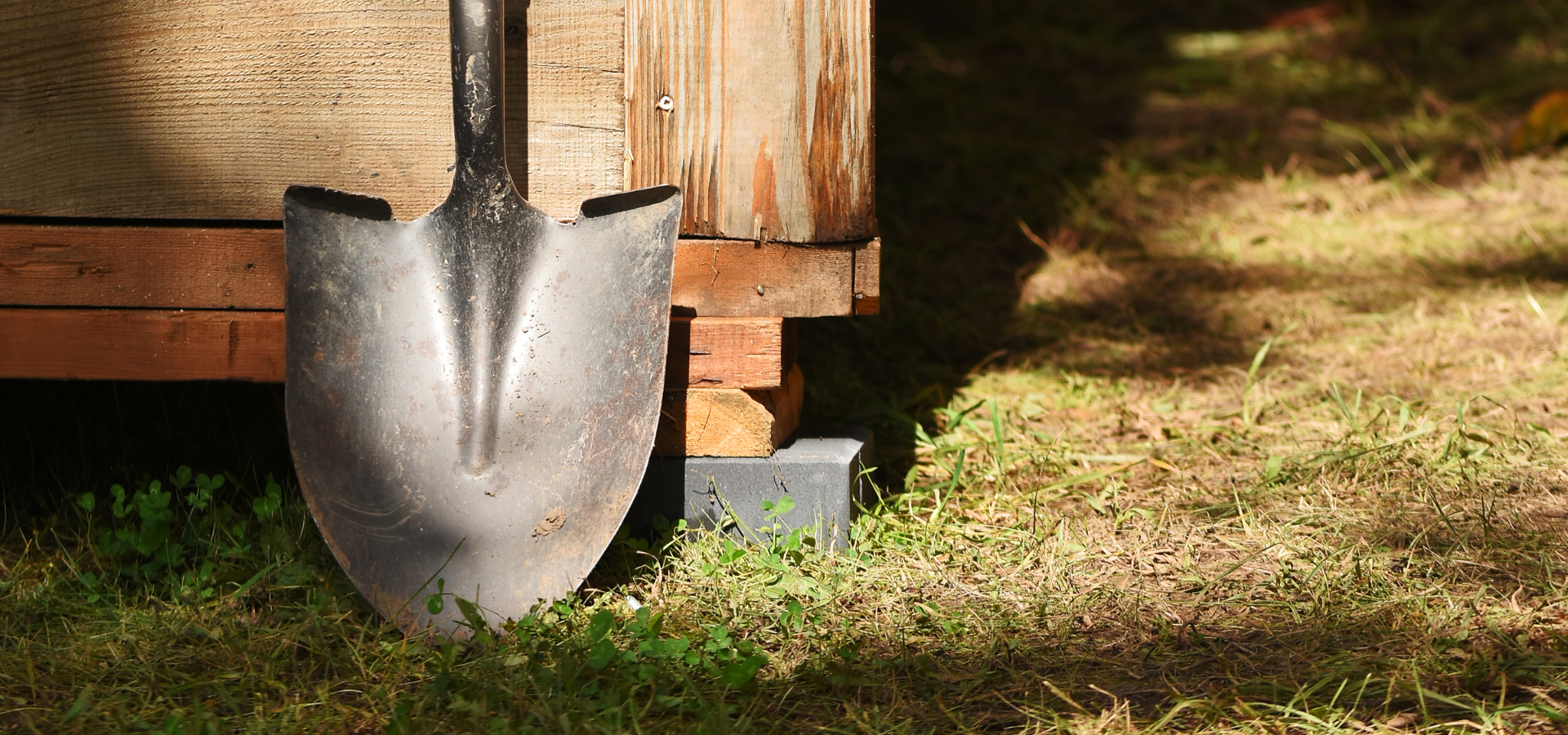 A garden spade leaning against a shed